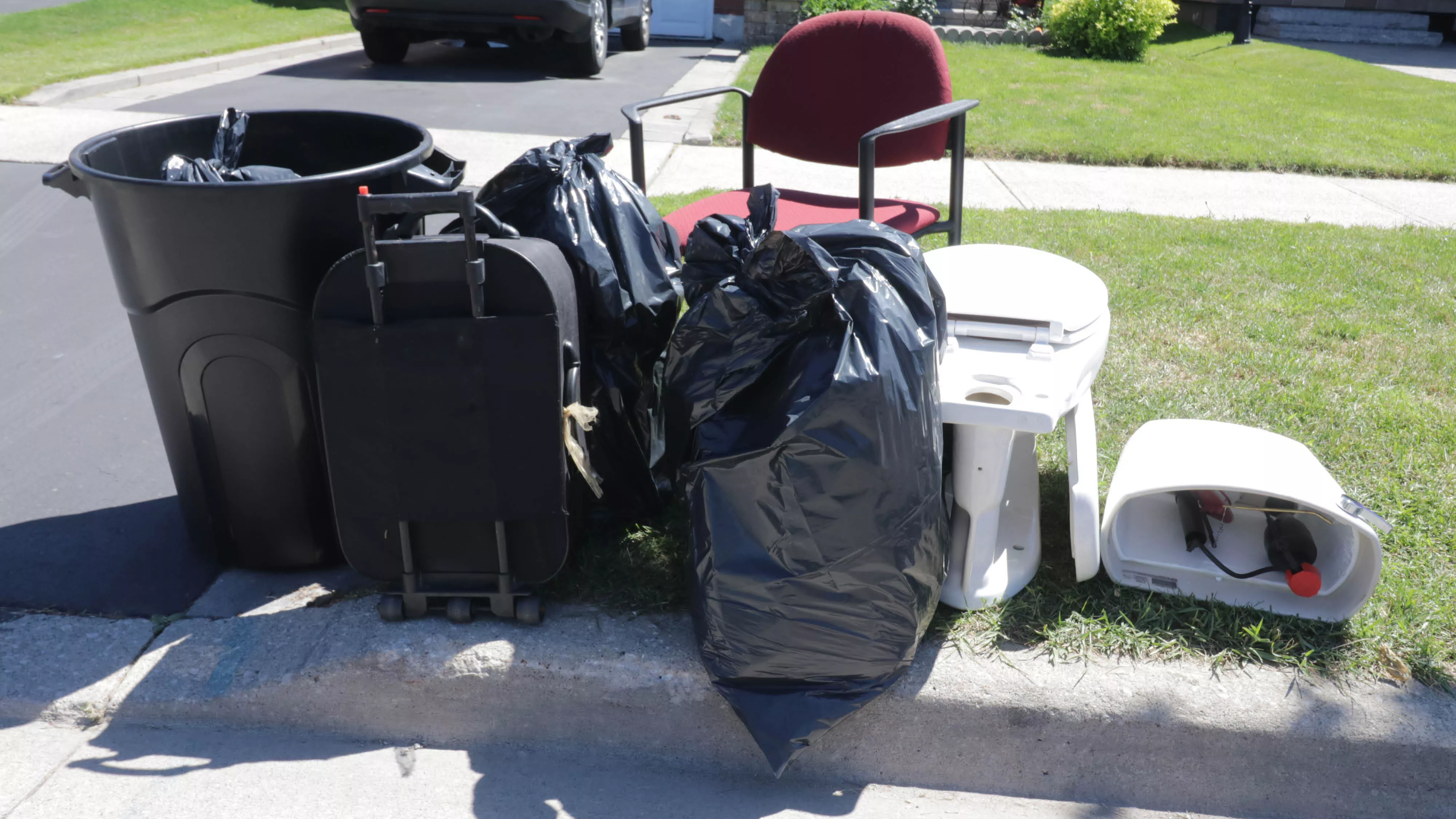 garbage bags, toilet, chair at the curb